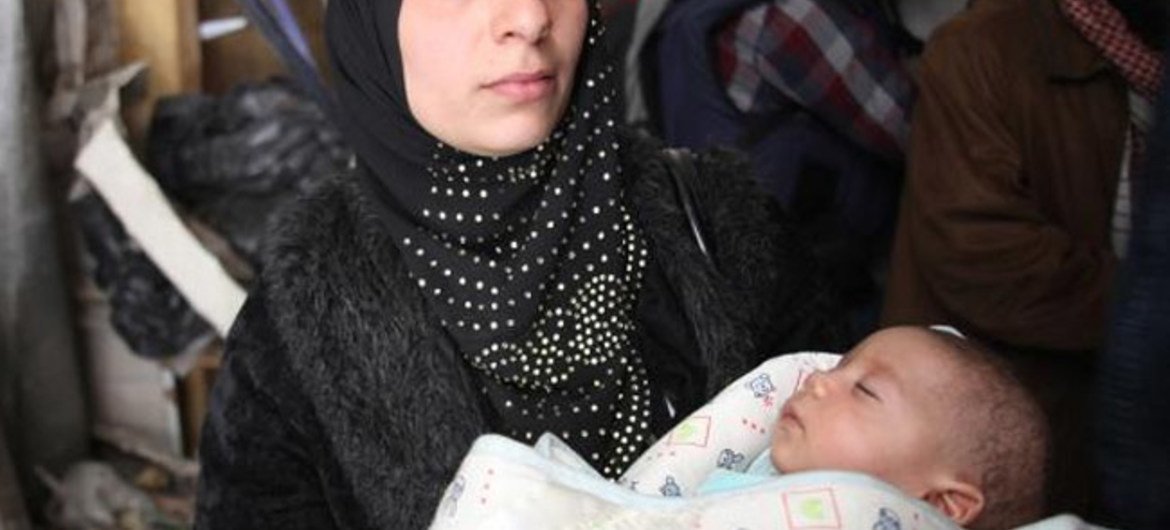 叙利亚的一位母亲抱着自己的孩子。联合国近东巴勒斯坦难民救济和工程处图片/Taghrid Mohammad