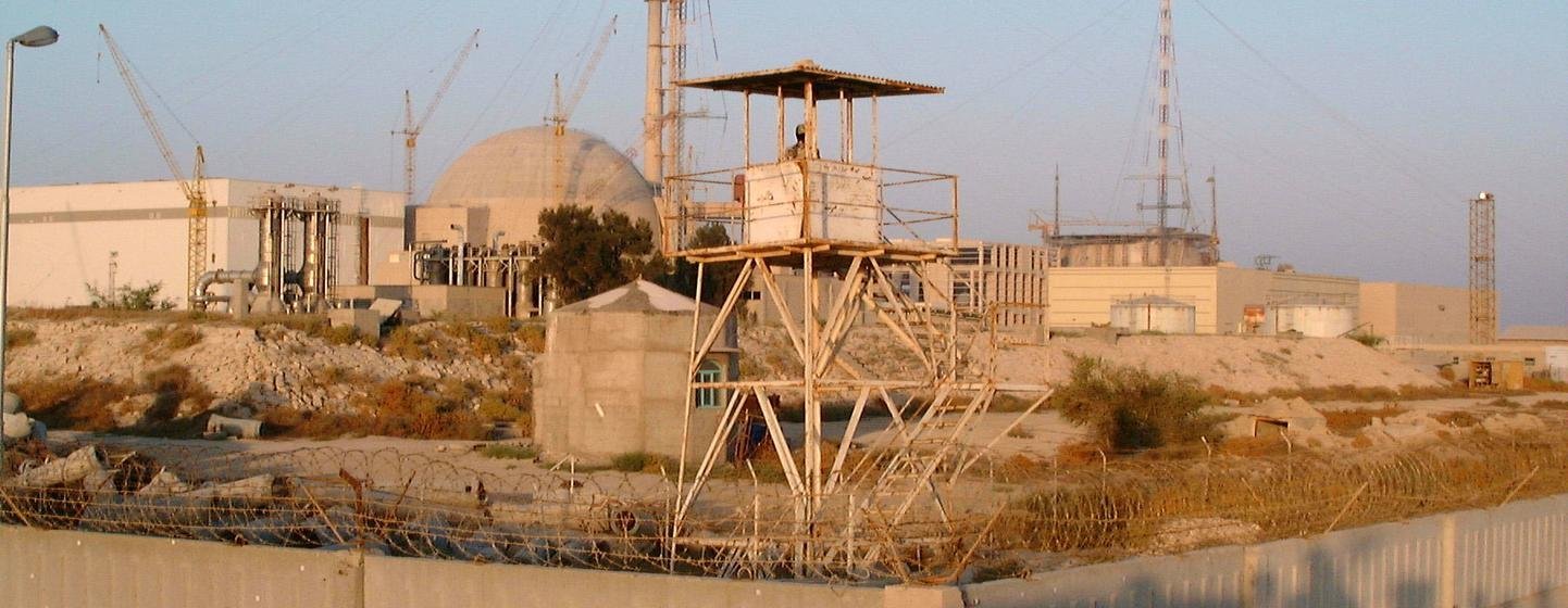 Une centrale nucléaire iranienne en construction, avec un grand bâtiment de réacteur en forme de dôme, entouré de clôtures de sécurité et de tours de surveillance.