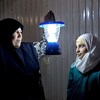 Syrian refugee Umfadi holds a solar powered lamp beside her 13-year-old niece Rama in her shelter at the Azraq refugee camp in Jordan.