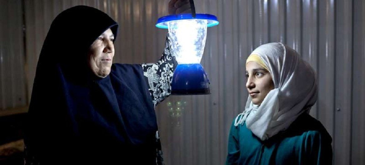 Syrian refugee Umfadi holds a solar powered lamp beside her 13-year-old niece Rama in her shelter at the Azraq refugee camp in Jordan.