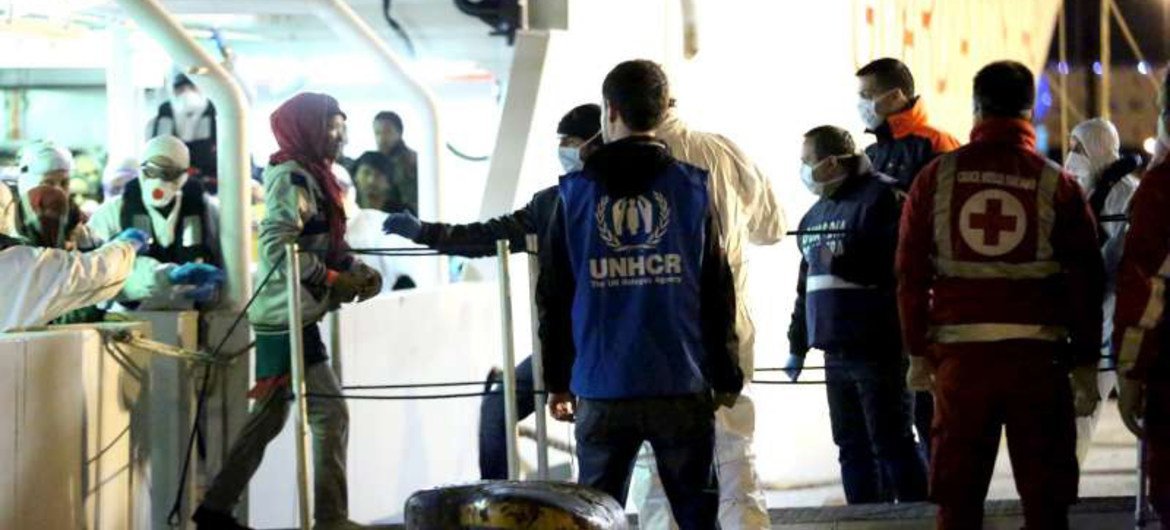 A UNHCR staff member watches as people rescued from the Mediterranean disembark from an Italian Coastguard vessel at Palermo, Sicily, on Tuesday 14 April 2015.