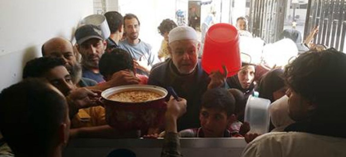 المدنيون النازحون من مخيم اليرموك يحصلون على وجبة ساخنة في ملجأ جماعي في يلدا، سوريا. المصدر: الأونروا