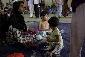 A rescued boat woman and her two children eat some welcome food at a centre in Kuala Cangkoi, Indonesia.