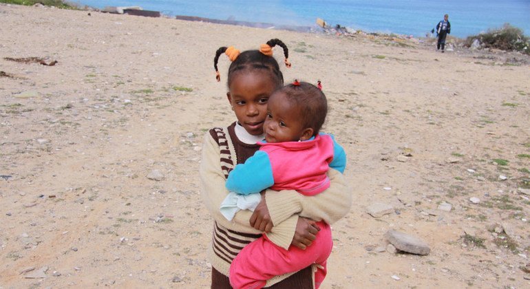 A girl displaced by violence on the outskirts of Tripoli, LIbia, takes care of her younger sister.  Photo UNHCR/L.  dobbs