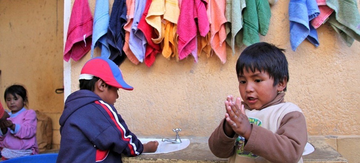 Two small children wash their hands with soap at a hand-washing station at the Sayariy Warmi early childhood development centre in Sucre, Bolivia.