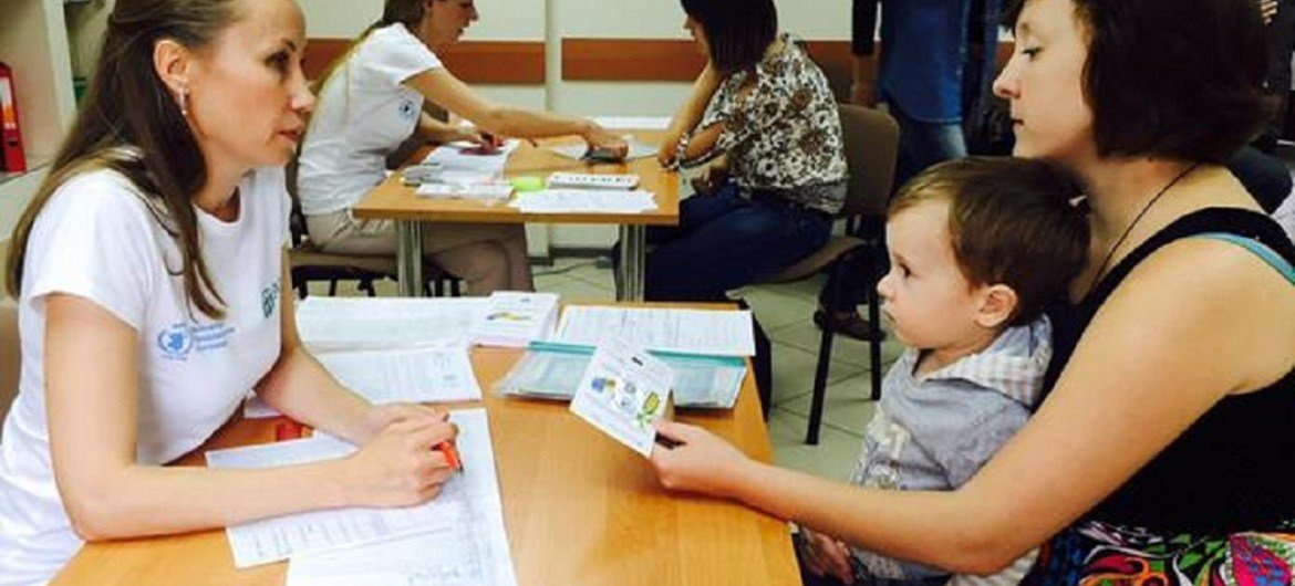 A mother and son receiving a WFP food voucher, distributed by NGO partner, ADRA, in Sloviansk, Ukraine.