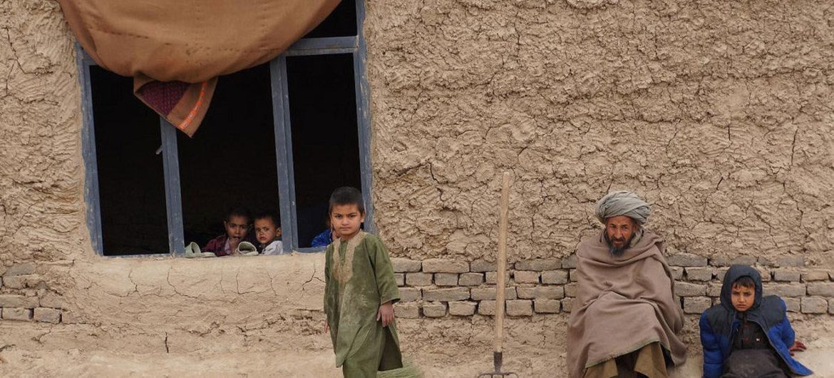 Members of a family sit outside their simple home in northern Afghanistan's Faryab province.