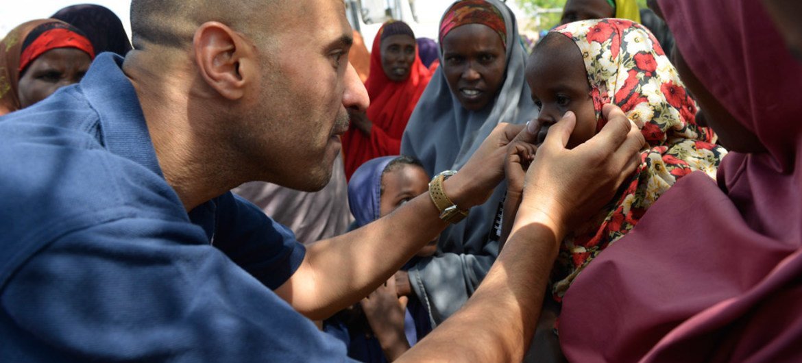 World Health Organization (WHO) official, Dr. Ahmed El Ganainy, checks the eyes of a little girl during a joint humanitarian assessment mission to Marka, Somalia, on 9 July 2014.