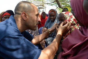 World Health Organization (WHO) official, Dr. Ahmed El Ganainy, checks the eyes of a little girl during a joint humanitarian assessment mission to Marka, Somalia, on 9 July 2014.
