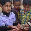 Pakistani children hold the remains of a shell that fell during clashes with India in Kashmir.