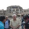 负责人道主义事务的副秘书长奥布莱恩2015年8月访问也门期间，与地方官员和媒体人员站在阿姆兰被空袭摧毁的政府大楼前。人道协调厅图片/Philippe Kropf