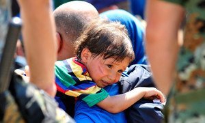 On 26 August 2015, a distressed child rests over the shoulder of the man carrying him, in the town of Gevgelija, on the border with Greece and the former Yugoslav Republic of Macedonia.