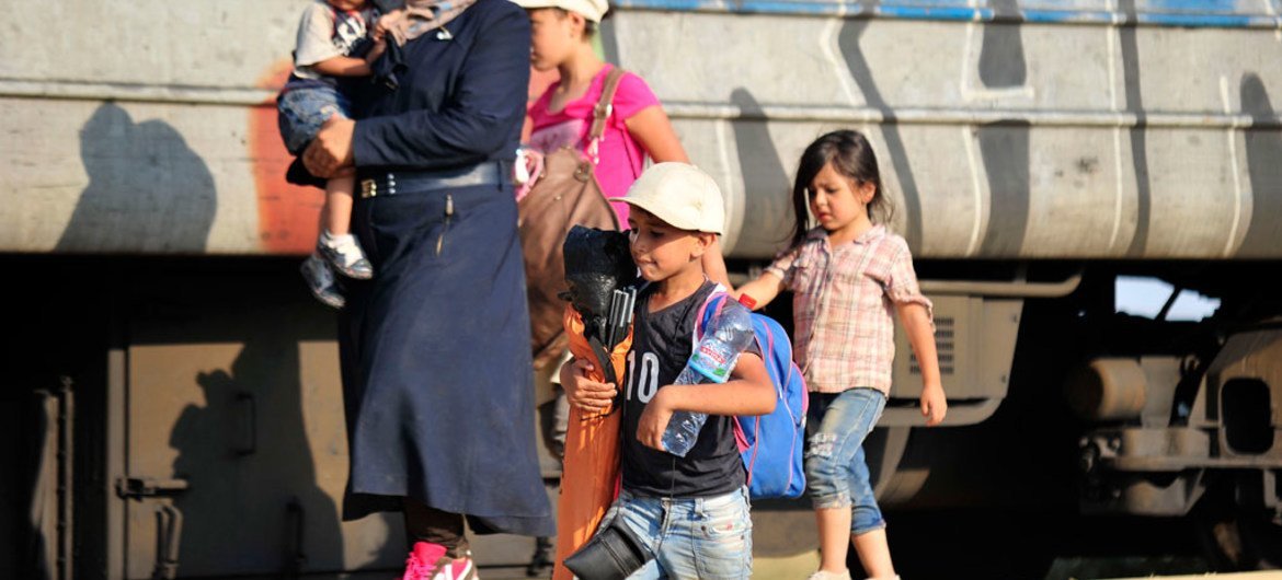 Una mujer carga a sus nietos en la frontera entre Grecia y la ex República Yugoslava de Macedonia. Esperan abordar un tren rumbo a Alemania. Foto: UNICEF/NYHQ2015-2083/Georgiev.