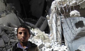 A boy stands outside a building damaged during fighting in Aleppo City, Syria.