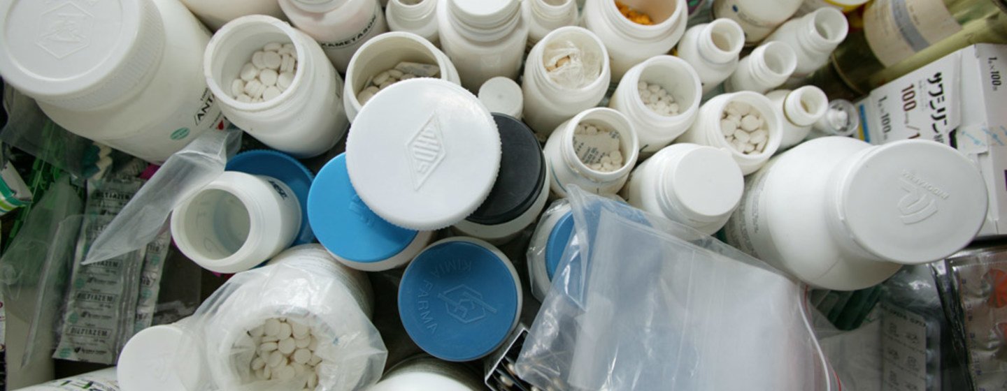 A collection of open medicine bottles containing various pills and capsules, alongside empty blister packs and plastic bags, all placed together on a surface.