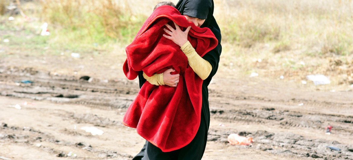 لاجئة تحمل طفلا على طريق موحل في بلدة بريسيفو جنوب صربيا ، على الحدود مع جمهورية مقدونيا اليوغوسلافية السابقة. المصدر: اليونيسف / توميسلاف جورجييف