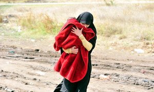 A woman carrying a child under a blanket walks on a muddy path in the southern Serbian town of Preševo, on the border with the former Yugoslav Republic of Macedonia.