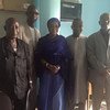 Five people, four men and one woman, stand together for a group photo in an office setting.