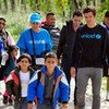L’Ambassadeur itinérant de l'UNICEF Orlando Bloom entourés des enfants et d’adultes marche en direction du centre d'accueil de réfugiés et de migrants près de la ville de Gevgelija, en ex-République yougoslave de Macédoine. Photo : UNICEF / Tomislav Georg