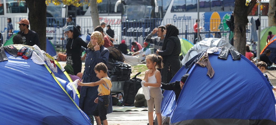 مجموعة من الأطفال والنساء والرجال اللاجئين، خارج  خيام  صغيرة في حديقة بالقرب من محطات الحافلات والقطارات في بلغراد، العاصمة الصربية. المصدر: اليونيسف / شوبكل