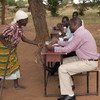 马拉维一位妇女向工作人员提供身份证明，以获得社会现金交换项目的支持。粮农组织图片/Amos Gumulira