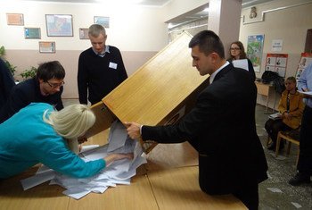 Member of a polling station committee for Belarus' presidential election empty a ballot box prior to counting in Minsk, 11 October 2015.