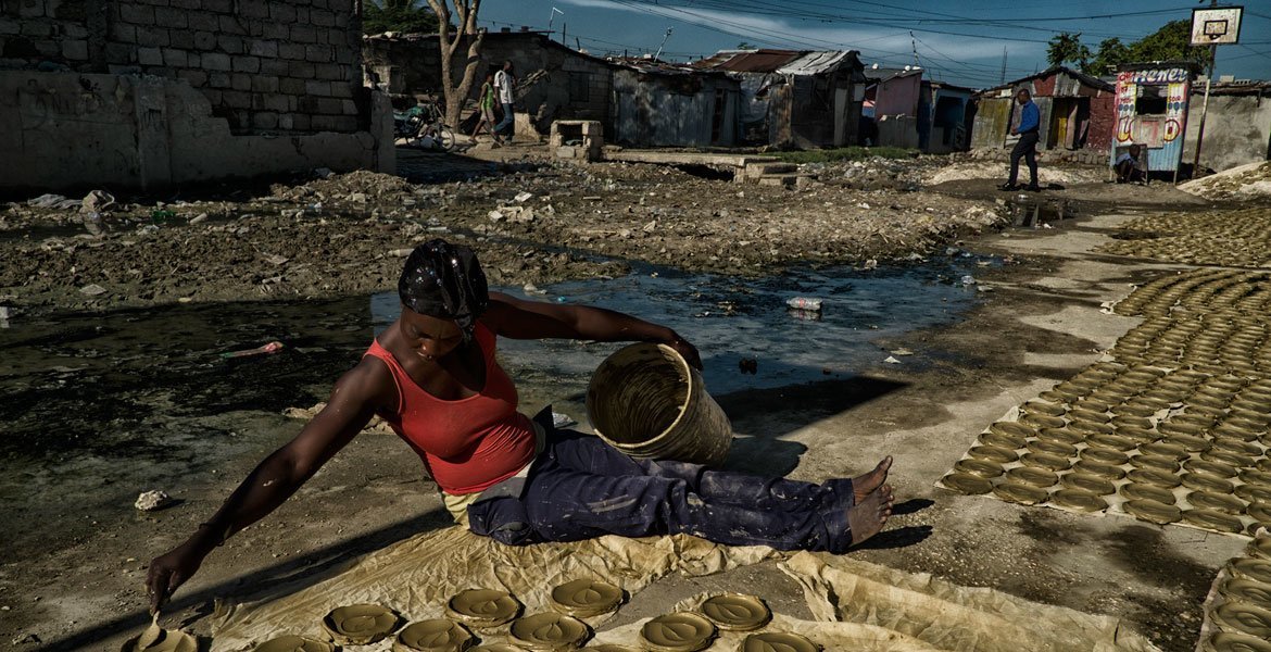 一名海地妇女正在为一家合作社制作“黏土蛋糕"，这种“蛋糕”用黏土、黄油加盐揉和，经日晒干燥制成，已成为海地极端贫穷与饥饿状况的象征。