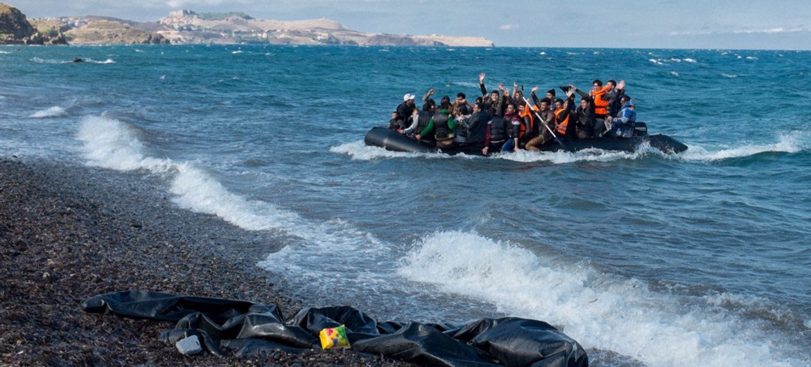 Newly-arriving refugees wave as the large inflatable boat they are in approaches the shore, near the village of Skala Eressos, on the island of Lesbos, in the North Aegean region of Greece.