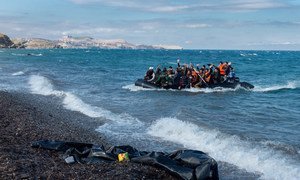 Newly-arriving refugees wave as the large inflatable boat they are in approaches the shore, near the village of Skala Eressos, on the island of Lesbos, in the North Aegean region of Greece.