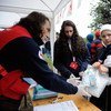 A woman carrying a young child receives relief items for her family, at a Red Cross station set up outdoors at the reception centre for refugees and migrants, in the town of Šid, Serbia, on the border with Croatia.