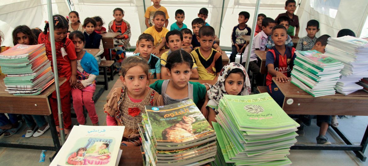Students sit in front of new textbooks in one of 12 tented classrooms at Al Takiya Al Kasnazaniya camp for internally displaced persons in Karkh District, Baghdad Governorate, Iraq.