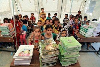 伊拉克流离失所儿童在教师里等待得到学习课本。