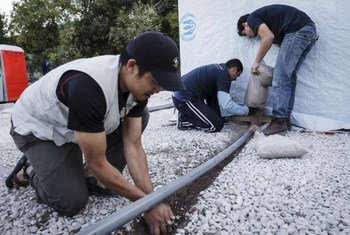 Members of Samaritan’s Purse, a UNHCR partner on the Greek island of Lesvos, install a drainage pipe at a sanitation facility.