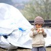 A young child eats a sandwich next to the tarpaulin that serves as a makeshift shelter, close to the town of Gevgelija, Former Yugoslav Republic of Macedonia, on the border with Greece (September 2015).