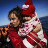 متطوعة على الجزيرة اليونانية ليسفوس تحمل طفلة بين ذراعيها، بعد لحظات من وصولها مع عائلتها في قارب مطاطي