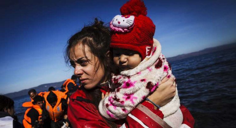 متطوعة على الجزيرة اليونانية ليسفوس تحمل طفلة بين ذراعيها، بعد لحظات من وصولها مع عائلتها في قارب مطاطي