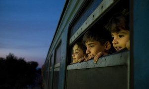 Les enfants regardent par la fenêtre de train dans un centre d'accueil pour les réfugiés et les migrants situé dans l'ex-République yougoslave de Macédoine.