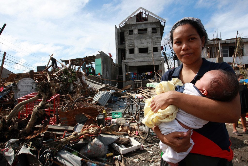 Une femme et son bébé au milieu des débris et d'autres destructions causées par le typhon Haiyan aux Philippines, en 2013.