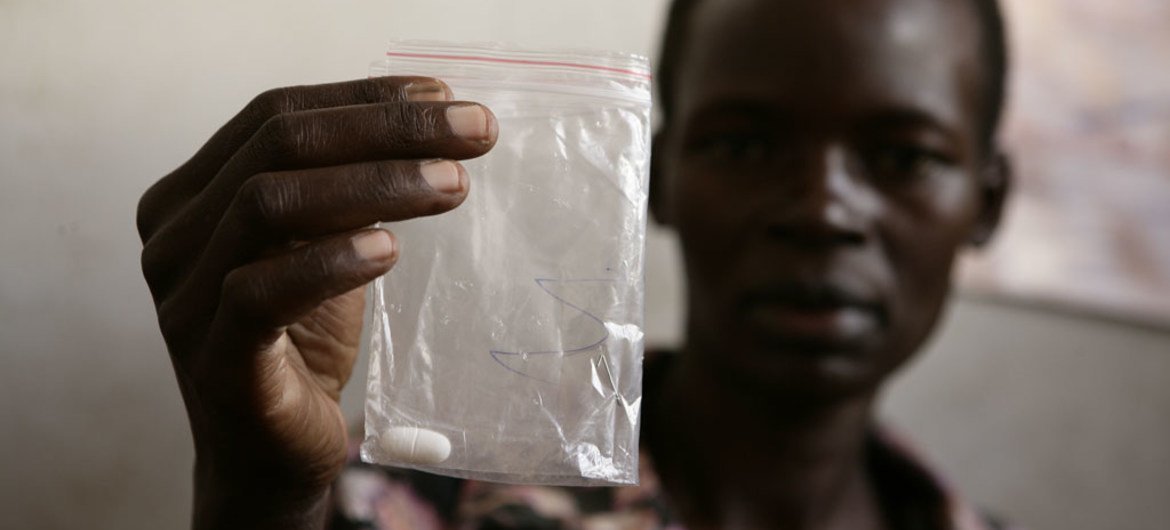 In Uganda, 29 year old Christine Adokorach holds a tablet of Niverapine, an antiretroviral drug, wrapped in a sealed plastic bag.