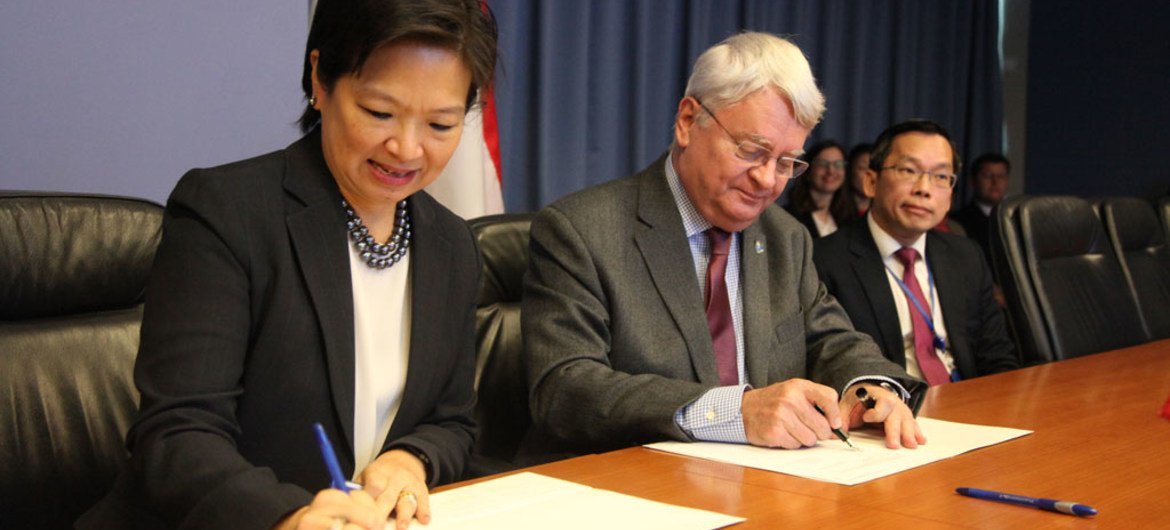 Under-Secretary-General for Peacekeeping Operations, Hervé Ladsous (centre) and Ambassador Karen Tan (left) of Singapore sign Memorandum of Understanding to work collaboratively on software development in support of UN Peacekeeping.