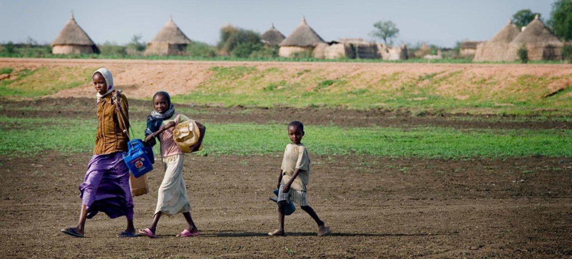 Children carry jerrycans and other containers on their way to collect water in El Khatmia Village, Gadaref state, Sudan.