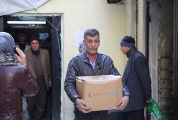 A Syrian man carries food provided by WFP.
