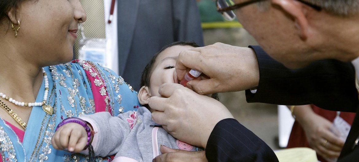 Secretary-General Ban Ki-moon administers a dose of a polio vaccine to a child brought by its mother to the United Nations complex in  New Delhi, India. October 2008.