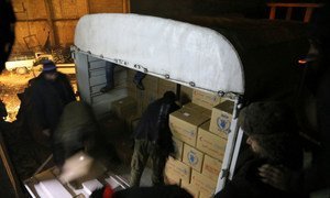Trucks, loaded with enough food to feed 40,000 people for one month in Madaya, Syria, are unloaded in the dark on arrival on 11 January 2016.
