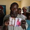 Dans le camp pour personnes déplacées de Gire 1, près de Yola, au Nigéria, un père tient des photos de sa fille aînée, de 18 ans, et de son fils de 6 ans, tous deux enlevés par des membres de Boko Haram lors d'une attaque de son village.