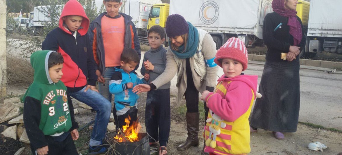 UNICEF Representative in Syria Hanaa Singer (center) speaks with children around a fire near the last checkpoint before Madaya town on 14 January 2016.