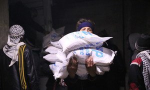 In Madaya, Syria, local community members help offload and distribute humanitarian aid supplies.