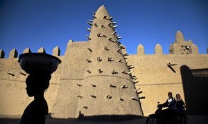 Residents of Timbuktu pass by Djingareyber Mosque, one of the historical architectural structures  along with Sankore Mosque, Sidi Yahia Mosque and sixteen mausoleums and holy public places  which together earned Timbuktu the designation of World Heritage Site by the UN Educational, Scientific and Cultural Organization (UNESCO).