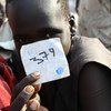 In March 2015, a boy holds his registration number following a ceremony formalizing his release from the South Sudan Democratic Army (SSDA) Cobra Faction, in Lekuangole village, in Jonglei State. UNICEF/UNI181538/McKeever