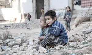 In Aleppo, Syria, four-year-old Esraa and her brother Waleed, three, sit on the ground near a shelter for internally displaced persons.